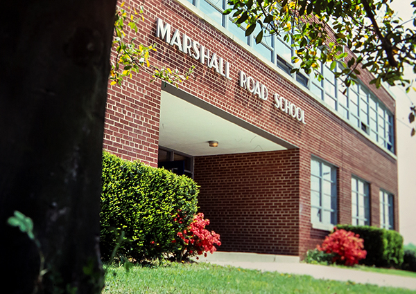 Color photograph from a 35 millimeter slide of the main entrance of Marshall Road Elementary School. The photograph is undated, but is believed to have been taken in the 1980s. It is springtime and the flowers in front of the school are in bloom.  